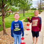 Photo of Eli Claypool and Ayden Godina with hummingbird feeders