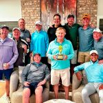 group of men in living room, one holding tennis trophy