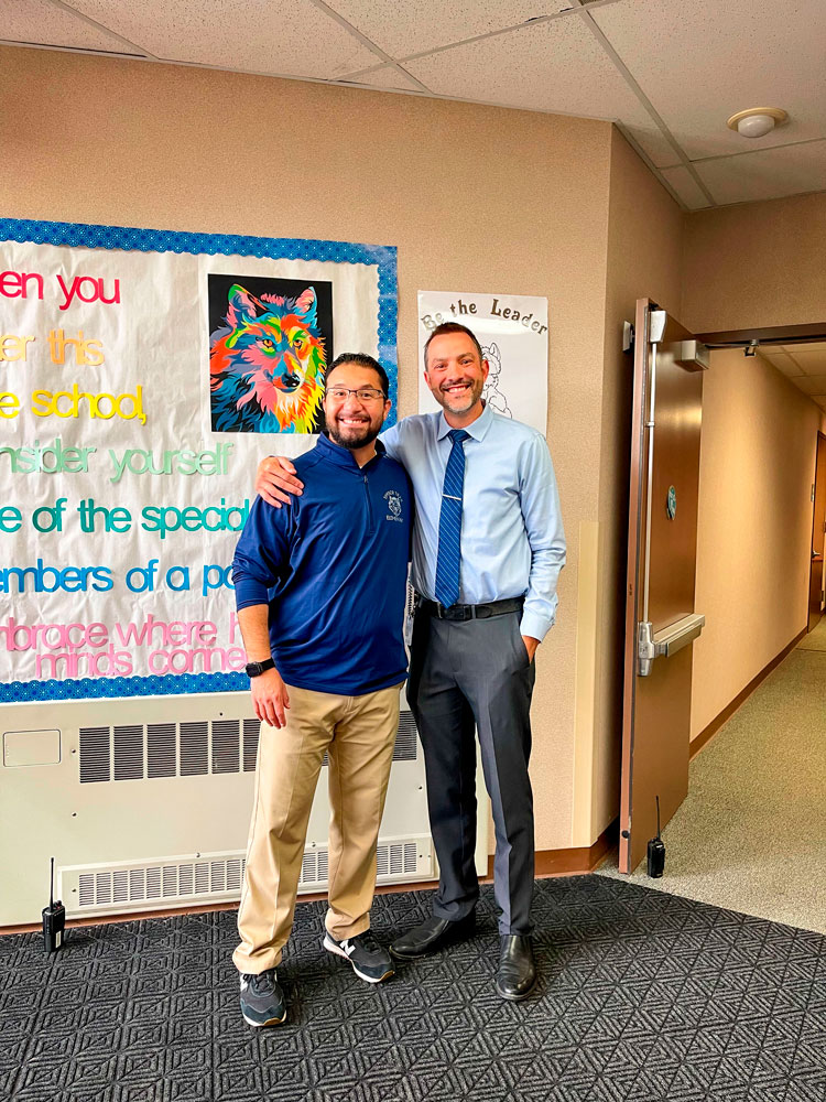 two men stand in school hallway